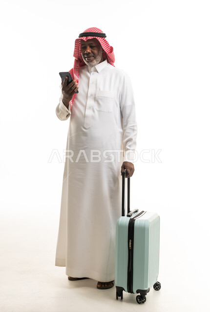 رجل سعودي مسن مع حقيبة سفر وهاتف ذكي