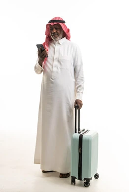 رجل سعودي مسن مع حقيبة سفر وهاتف ذكي