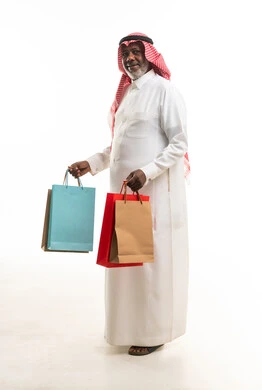 رجل سعودي مسن يحمل أكياس تسوق بخلفية بيضاء