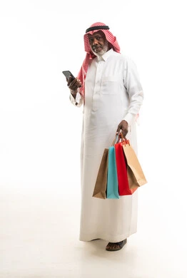رجل سعودي مسن يحمل حقائب تسوق وهاتف ذكي