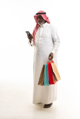 رجل سعودي مسن مع حقائب تسوق وهاتف ذكي