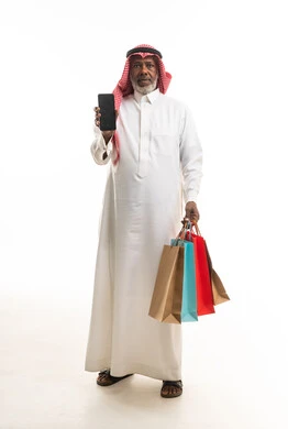 رجل سعودي مسن يحمل أكياس تسوق وهاتف ذكي