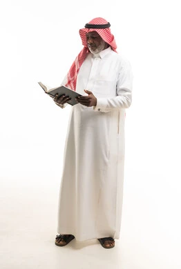 رجل أسود مسن بالزي العربي التقليدي يقرأ كتاب