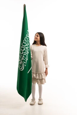 طفلة سعودية تمسك العلم الوطني على خلفية بيضاء