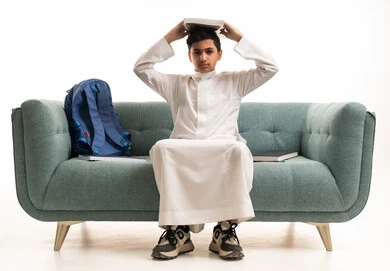 طالب سعودي بالثوب التقليدي يحمل كتابا