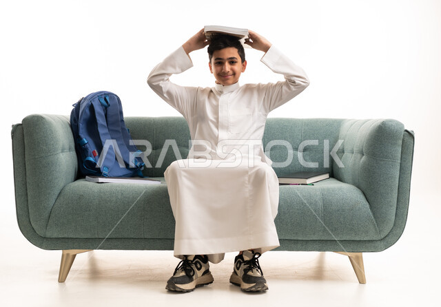 طفل سعودي بالثوب مع حقيبة مدرسية وكتب