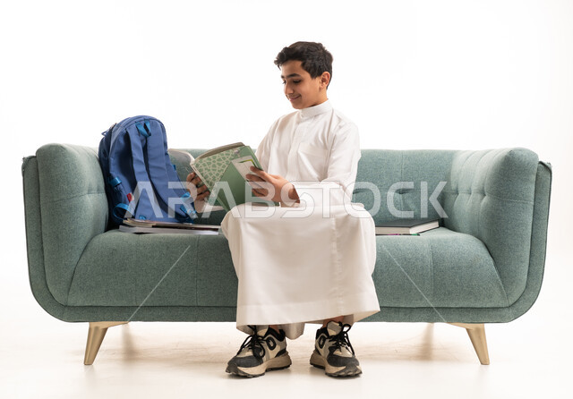 طالب سعودي بالثوب الأبيض يقرأ على الأريكة