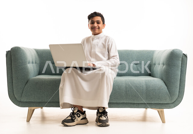 فتى سعودي مع لابتوب بالثوب التقليدي الأبيض