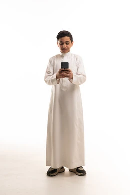 فتى سعودي بالثوب الأبيض يحمل هاتف ذكي في الاستوديو