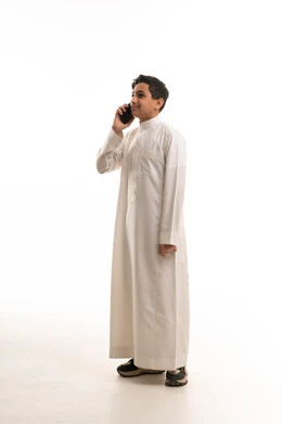 فتى سعودي بالثوب الأبيض يتحدث بالهاتف المحمول