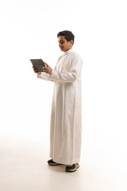Saudi Boy in White Thobe Holding Digital Tablet