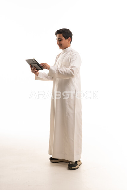 Saudi Boy in Thobe Using Tablet on White Background