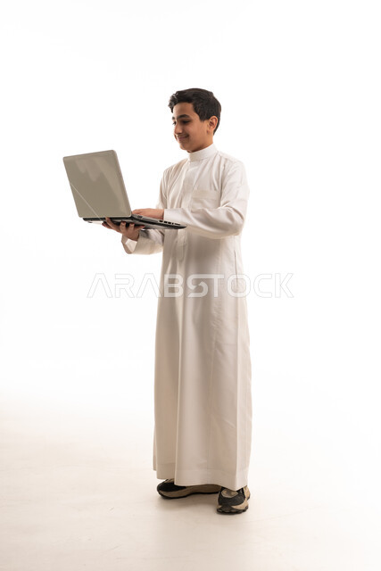 ولد سعودي بالثوب الأبيض يستخدم لابتوب خلفية بيضاء