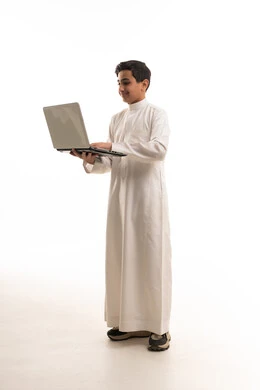 ولد سعودي بالثوب الأبيض يستخدم لابتوب خلفية بيضاء