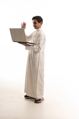 Saudi Boy in White Thobe Using Laptop on White Background