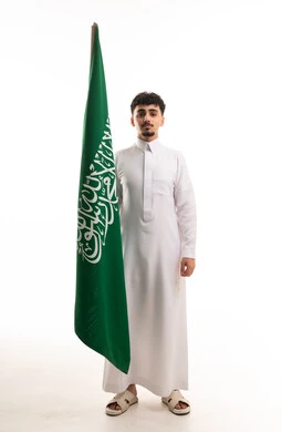 رجل سعودي يحمل العلم الوطني بالثوب التقليدي