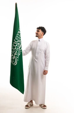 شاب سعودي يمسك العلم الوطني بالثوب التقليدي