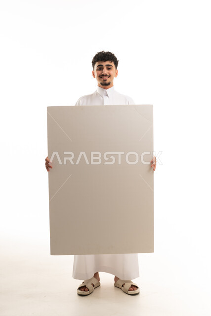 رجل سعودي بالثوب التقليدي يحمل لوحة إعلانية فارغة
