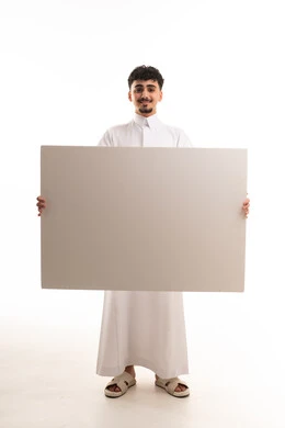 شاب سعودي بالثوب التقليدي يحمل لوحة بيضاء فارغة