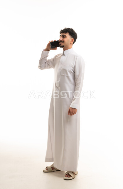 رجل سعودي بالثوب التقليدي يستخدم الهاتف الذكي