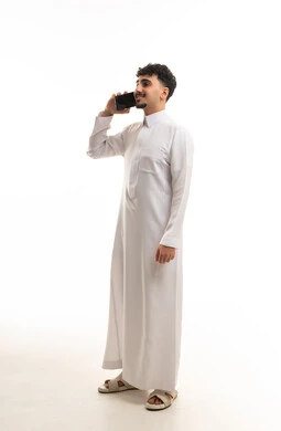 رجل سعودي بالثوب التقليدي يستخدم الهاتف الذكي