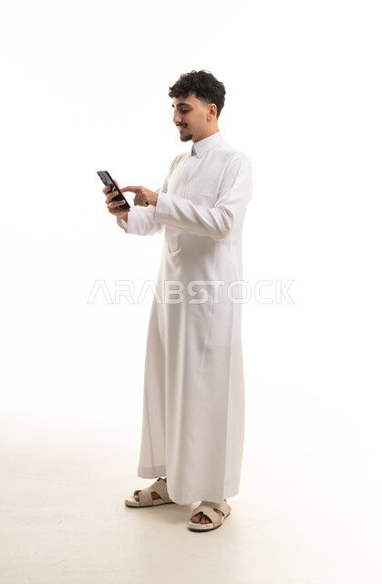رجل سعودي بالثوب الأبيض يستخدم الهاتف المحمول