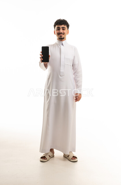 رجل سعودي بالثوب التقليدي يمسك هاتف ذكي