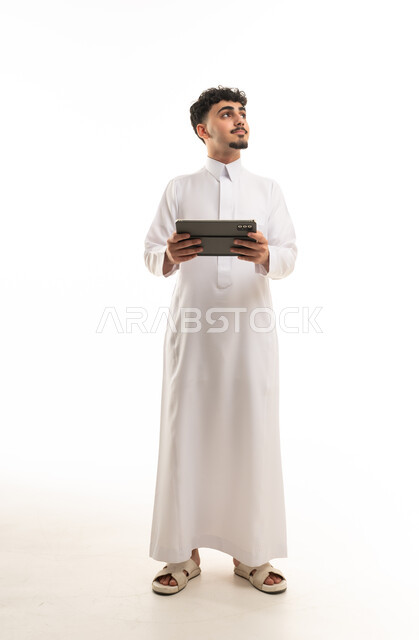 رجل سعودي بالثوب التقليدي يحمل جهاز لوحي رقمي