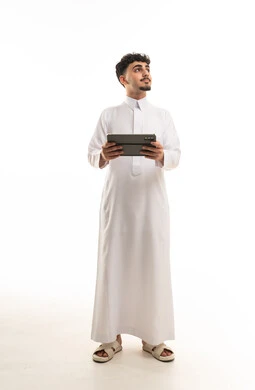 رجل سعودي بالثوب التقليدي يحمل جهاز لوحي رقمي