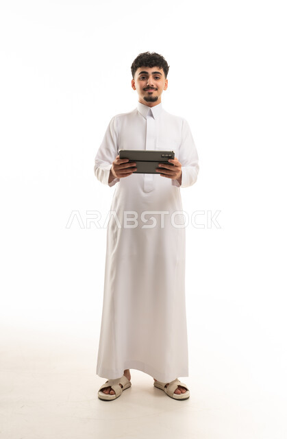 رجل سعودي بالثوب التقليدي يمسك جهازاً لوحياً