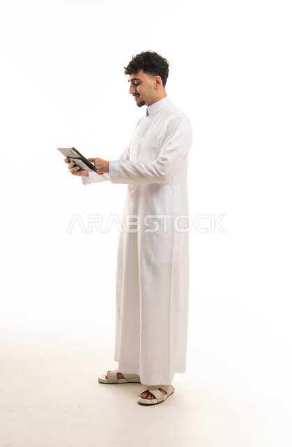 رجل سعودي بالثوب الأبيض يستخدم جهاز لوحي