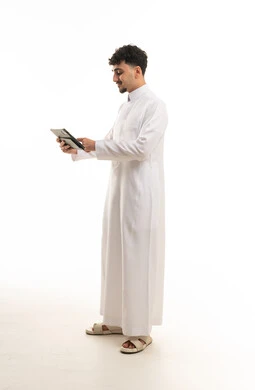 رجل سعودي بالثوب الأبيض يستخدم جهاز لوحي