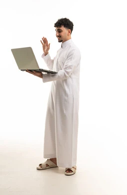 رجل سعودي بالثوب التقليدي يستخدم الكمبيوتر المحمول
