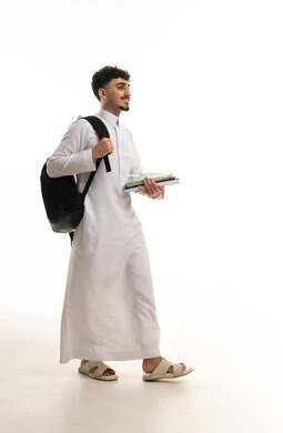 طالب سعودي يمشي حاملاً حقيبة ظهر وكتب دراسية
