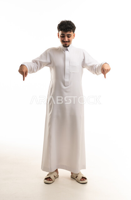 رجل سعودي بالثوب الأبيض يشير للأسفل في الاستوديو