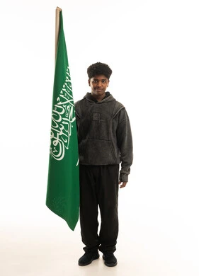 شاب سعودي يمسك علم المملكة العربية السعودية في استوديو