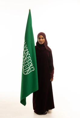 امرأة سعودية مع العلم الوطني بالعباية التقليدية
