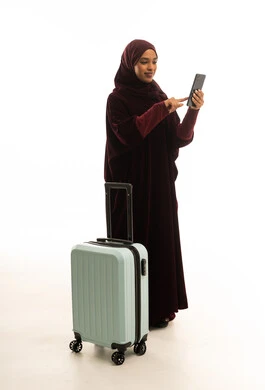 Saudi Woman with Suitcase Using Smartphone