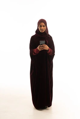 امرأة أفريقية بعباءة مخملية تستخدم الهاتف الذكي