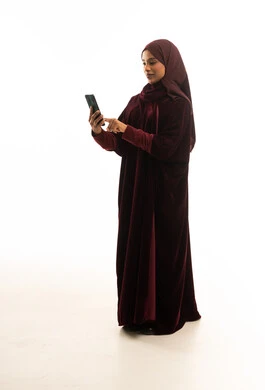 Saudi Woman in Burgundy Velvet Abaya Using Smartphone