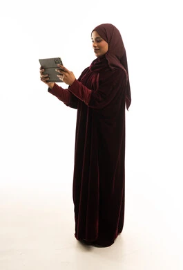 امرأة سعودية تستخدم جهازاً لوحياً بجلابية مخملية