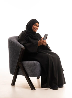 امرأة سعودية بالعباءة تستخدم الهاتف الذكي