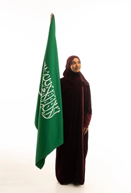 امرأة سعودية تحمل العلم الوطني للمملكة بخلفية بيضاء