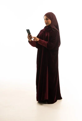Saudi Woman in Maroon Abaya Using Smartphone in Studio