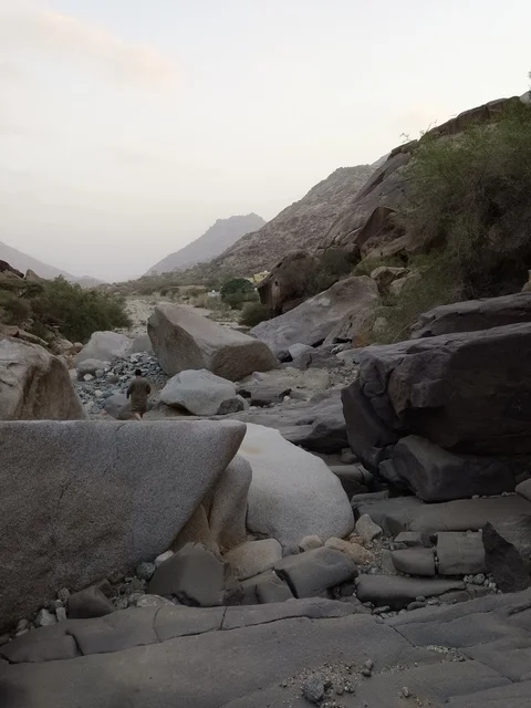 رجل يمشي في وادي جبال الباحة الصخري