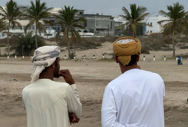 رجال عمانيون بالزي التقليدي على شاطئ رملي بعمان