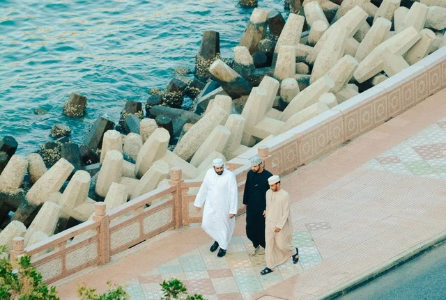 Omani Men Walking on Coastal Promenade Sultanate of Oman