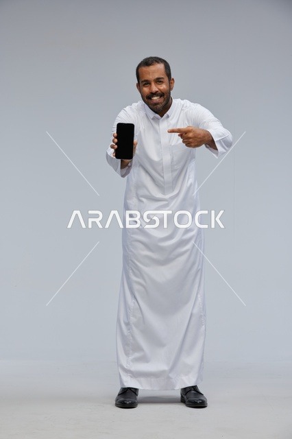 Saudi Man in White Thobe Pointing at Smartphone Screen