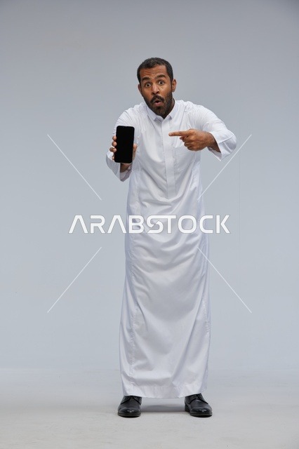 Saudi Man in White Thobe Pointing at Smartphone Screen