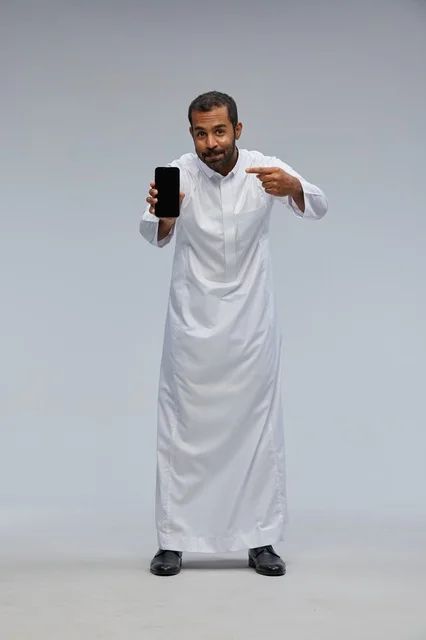 Saudi Man in White Thobe Pointing at Smartphone Screen